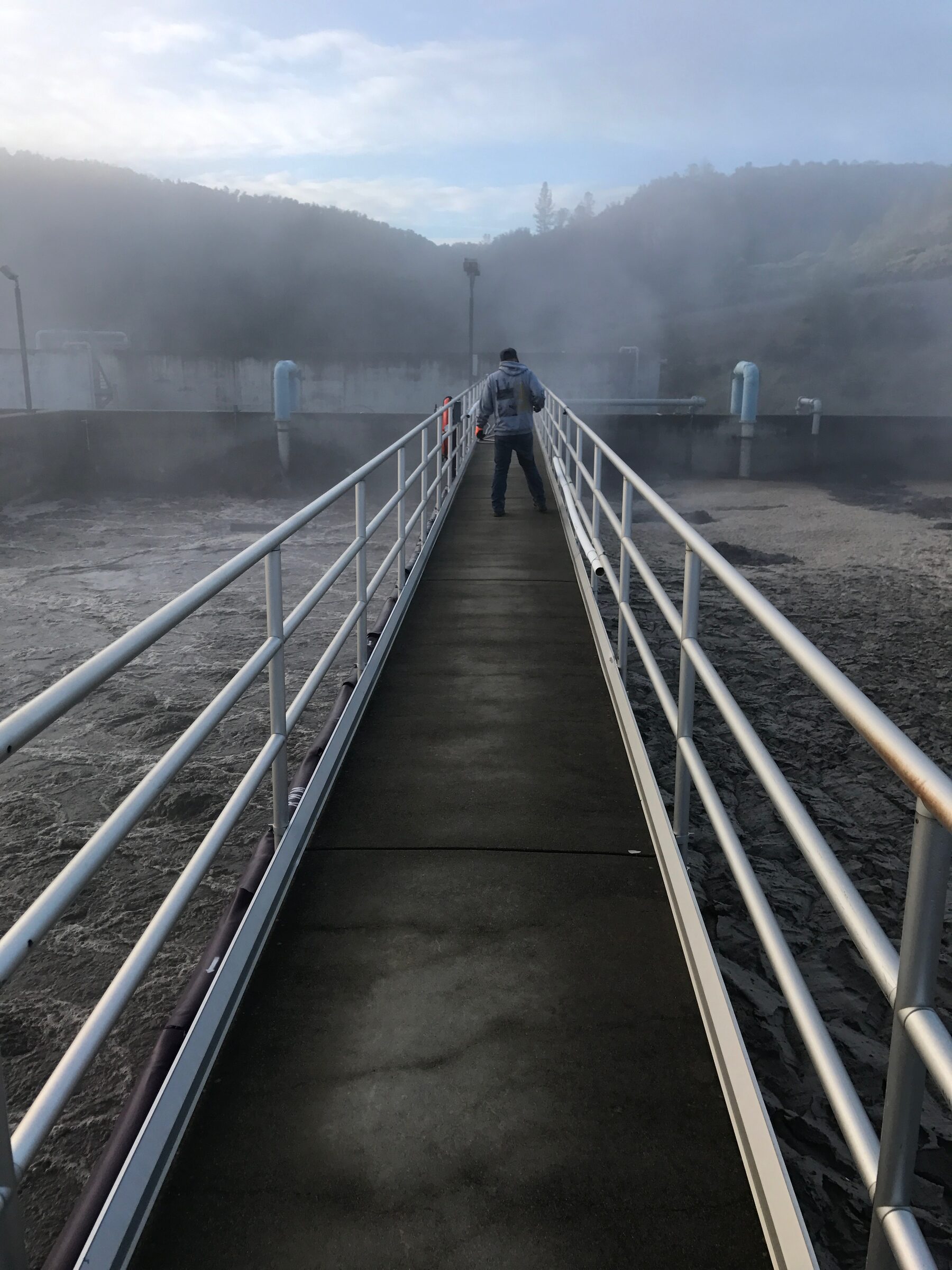 Fusion technician crossing a catwalk at a water treatment basin