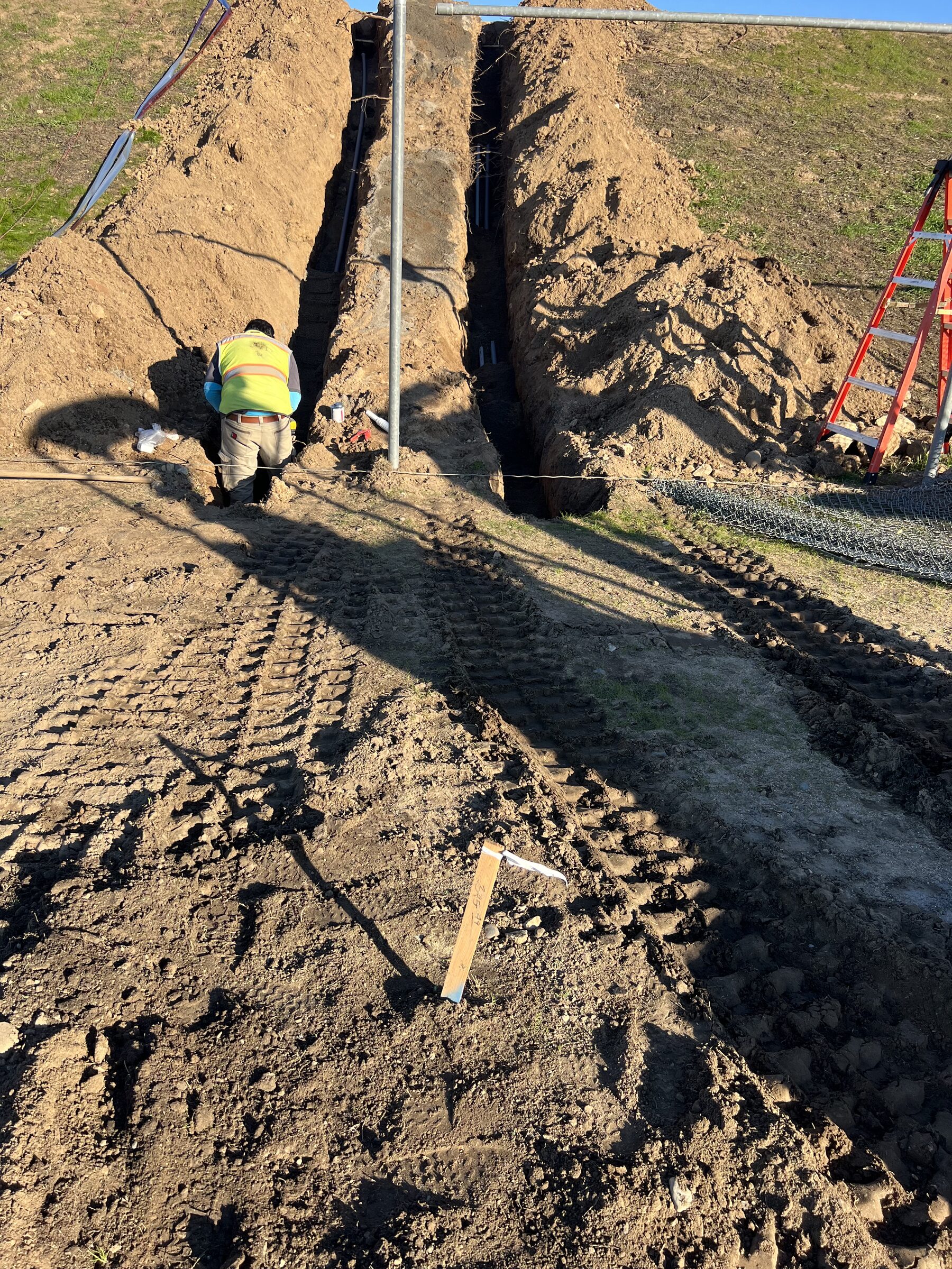 Fusion Electric crew member working a hillside trench on-site
